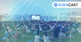 Bluetooth Auracast being used at a music festival, on a big screen with people watching and listening