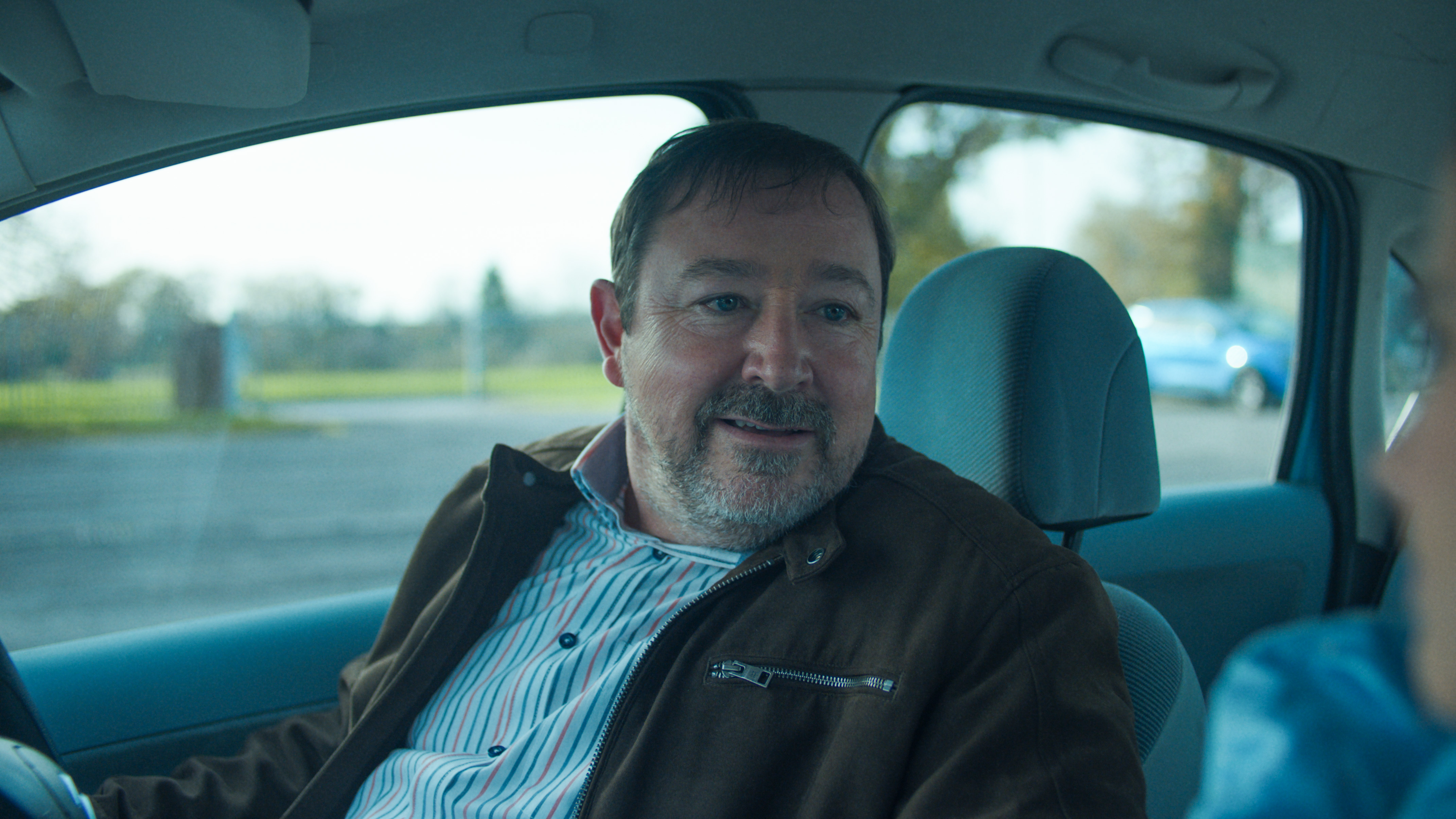 Graham played by Daniel Ryan sitting in a car talking to Billie.