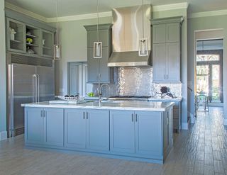 Metallic wall tiles in kitchen with blue cabinets