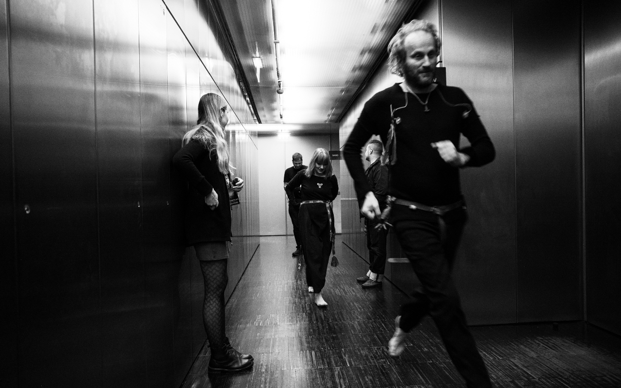 Members of Wardruna running down a backstage hall