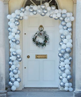 White front door decorated with white and silver balloon arch