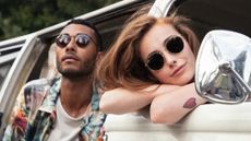 Couple posing outside car with sunglasses on 
