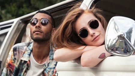 Couple posing outside car with sunglasses on