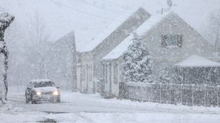 snow storm with car and house in background