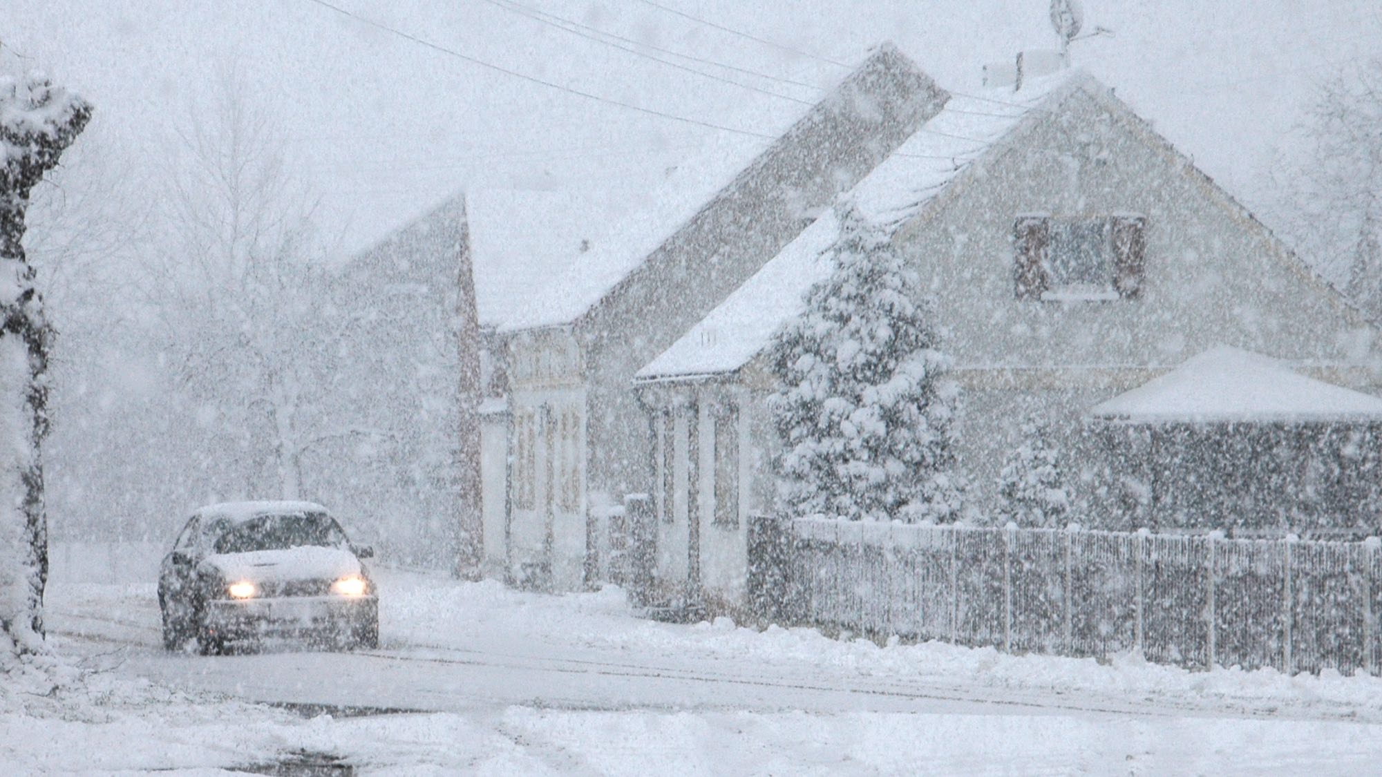 snow storm with car and house in background