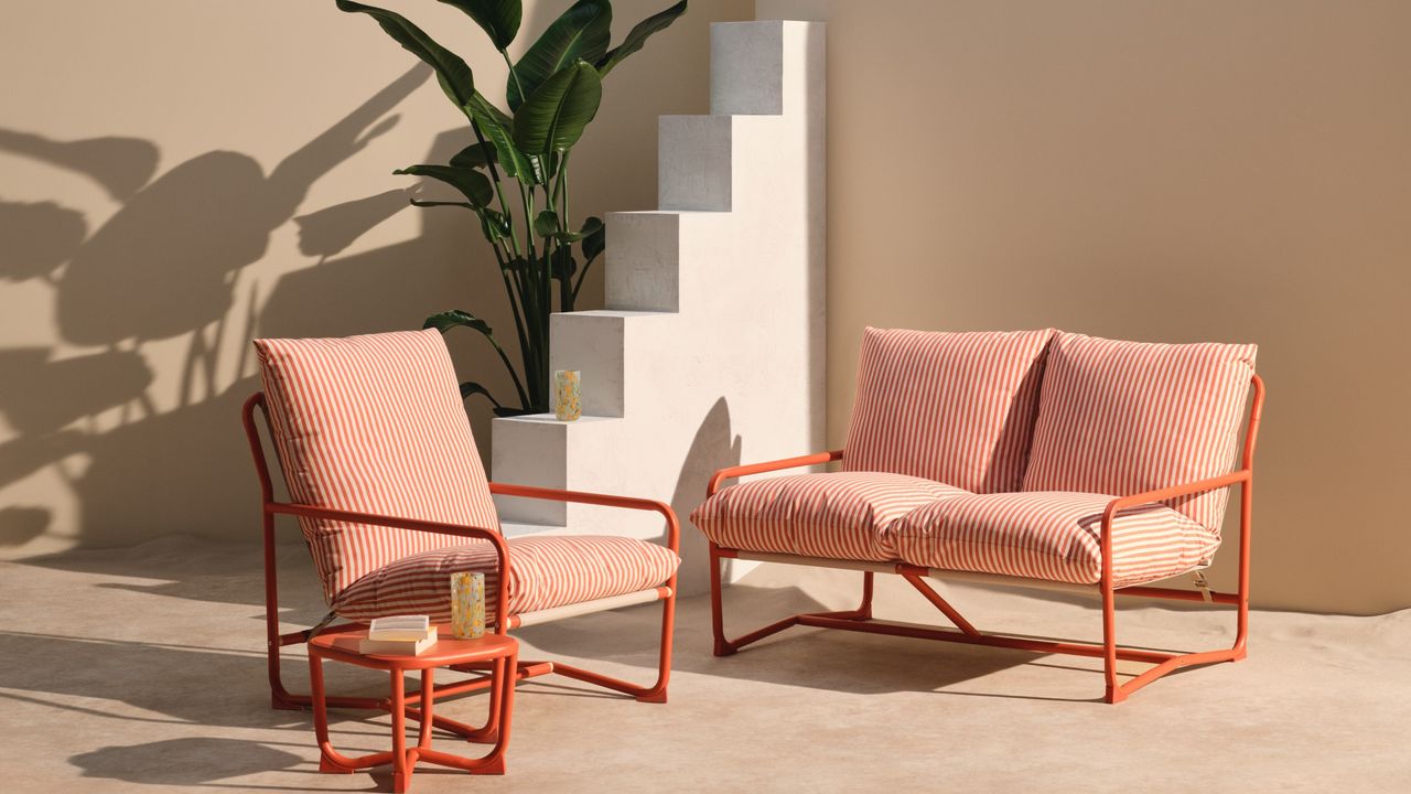 John Lewis Marcy Sling Garden Chair, 2-seater sofa and a coordinating side table in burnt orange set in sand with a palm in the background