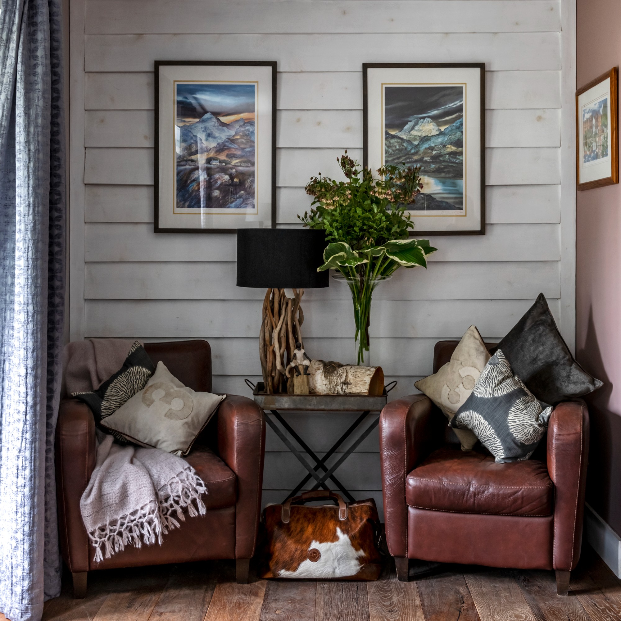 A small snug room with a white panelled wall and two brown leather armchairs