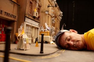 Bill Murray lying with eyes closed with his face on the road on the set of Wes Anderson movie Fantastic Mr Fox which makes Bill look like a giant