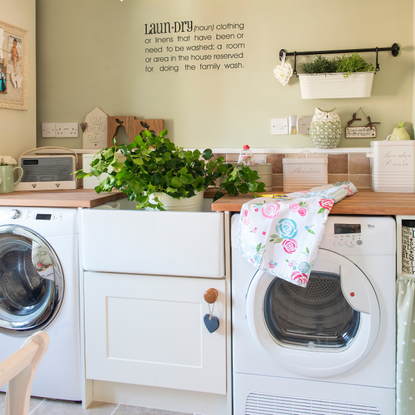 Green laundry room, wall decal, washing machine and dryer, floral bunting, wood worktops.