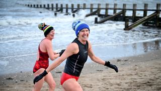 Two women wild swimmers go for a swim at Portobello beach in the snow, Scotland.