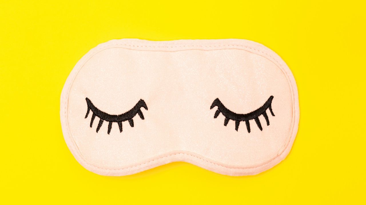 A sleep mask with embroidered eyelashes on the front 