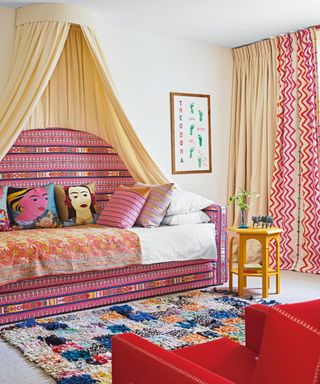 girl's bedroom with pink patterned sofabed with canopy, patterned rug and red armchair