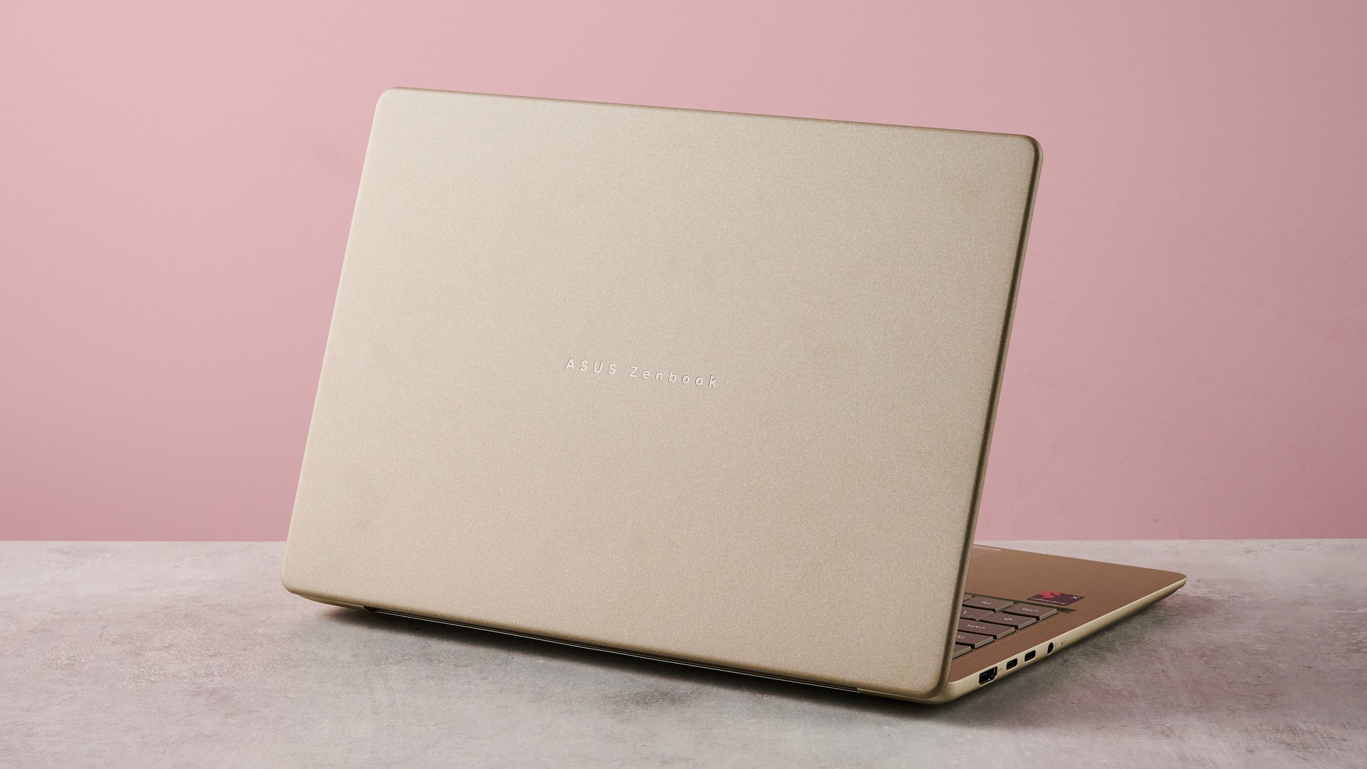 Rear three-quarter view of Asus Zenbook 14 2026 on desk with pink wall in background