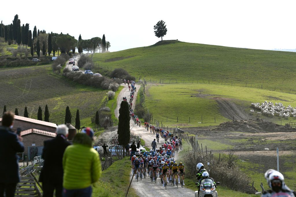 SIENA ITALY MARCH 06 The Peloton passing through Tuscany landscape during the Eroica 15th Strade Bianche 2021 Mens Elite a 184km race from Siena to Siena Piazza del Campo Gravel Strokes Sheep Fans Public StradeBianche on March 06 2021 in Siena Italy Photo by Tim de WaeleGetty Images