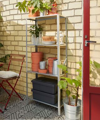 galvanised shelving for a shed with terracotta pots stacked up and plants on top