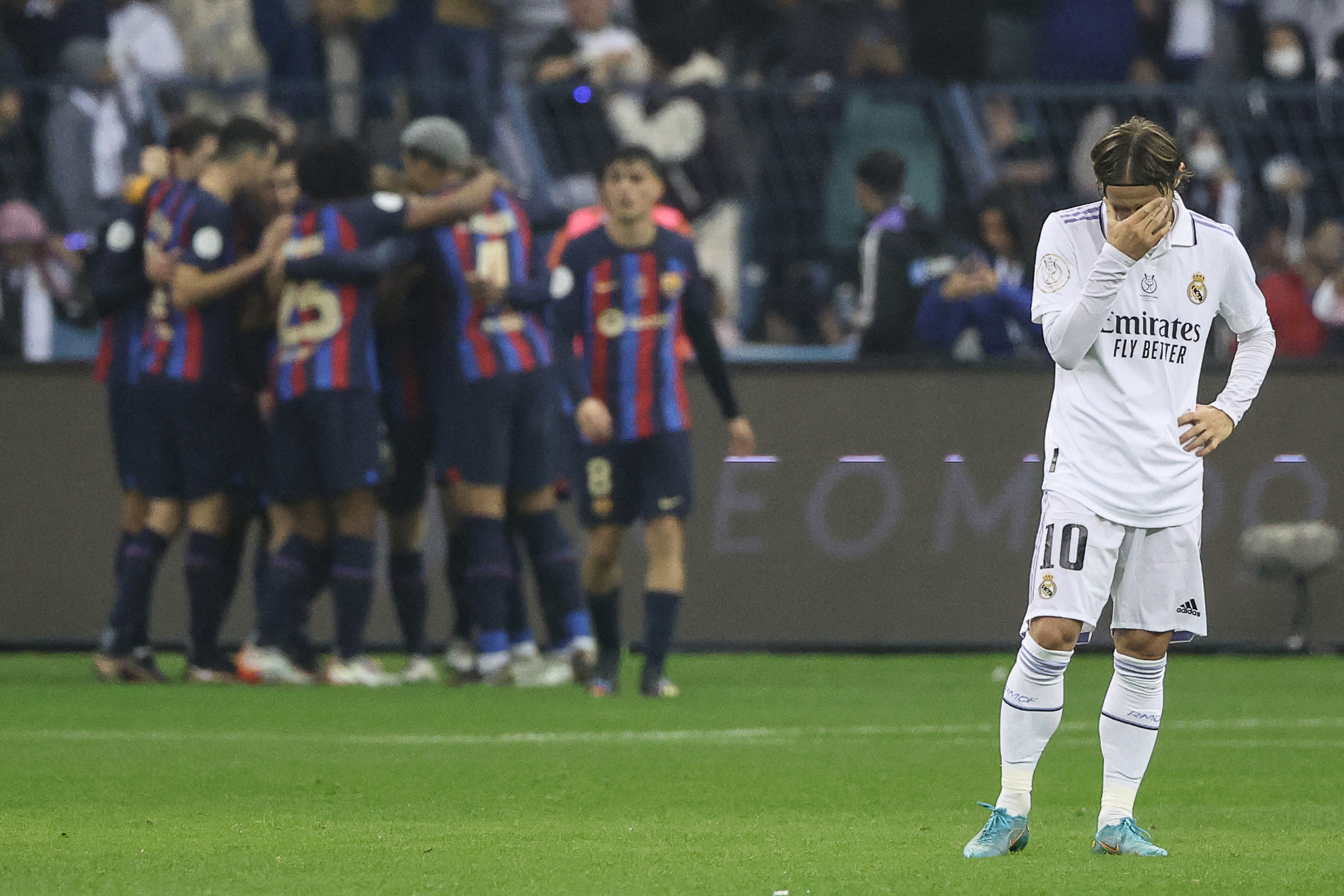 Luka Modric holds his head as Barcelona celebrate a goal against Real Madrid in the Supercopa de España final in January 2023.