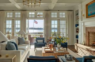 living room with white sofa blue chairs ocean view and feature brick fireplace