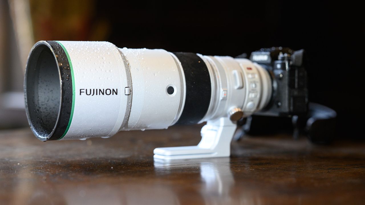 The Fujifilm XF 400mm F4.5 R LM OIS WR telephoto prime lens attached to a Fujifilm X-H2S camera, on a wooden table