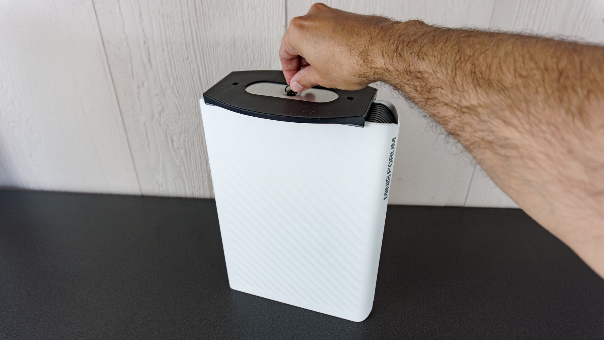 A person installing the Minisforum G1 Pro's vertical stand