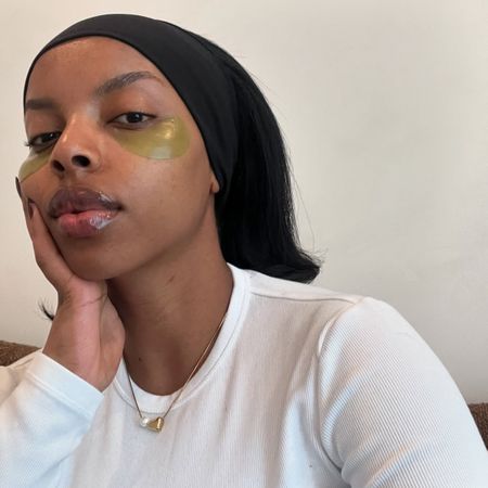 A woman doing skincare and wearing eye patches