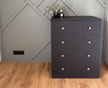 Ikea malm drawers painted black, in front of sage green wall 