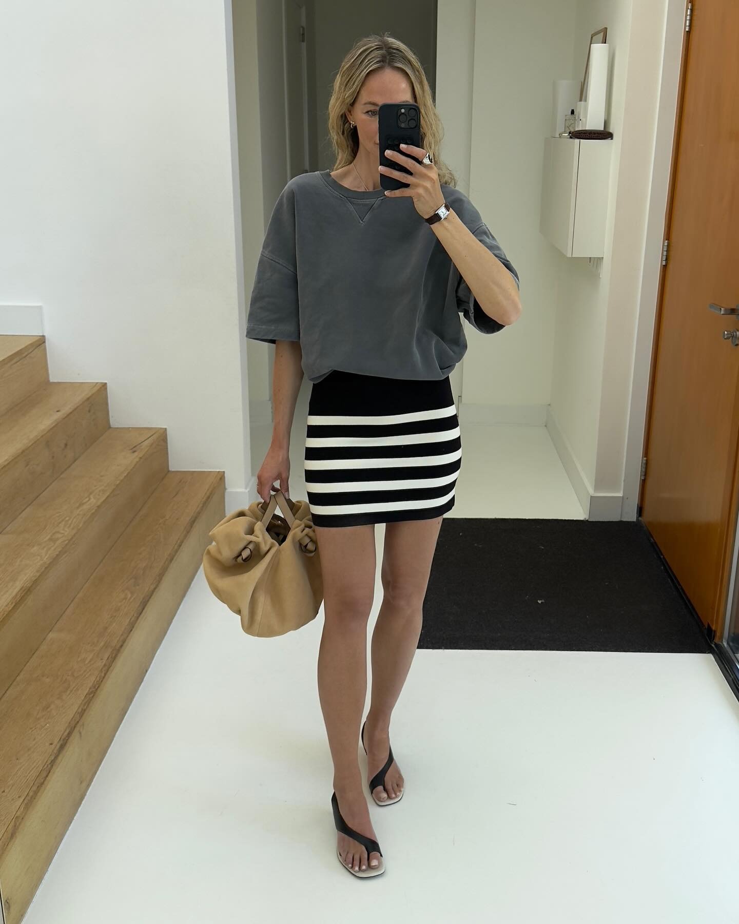European influencer wearing a tee, striped miniskirt, and toe-ring Toteme sandals