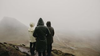 Hikers in the rain in Scotland look at the views down the glen