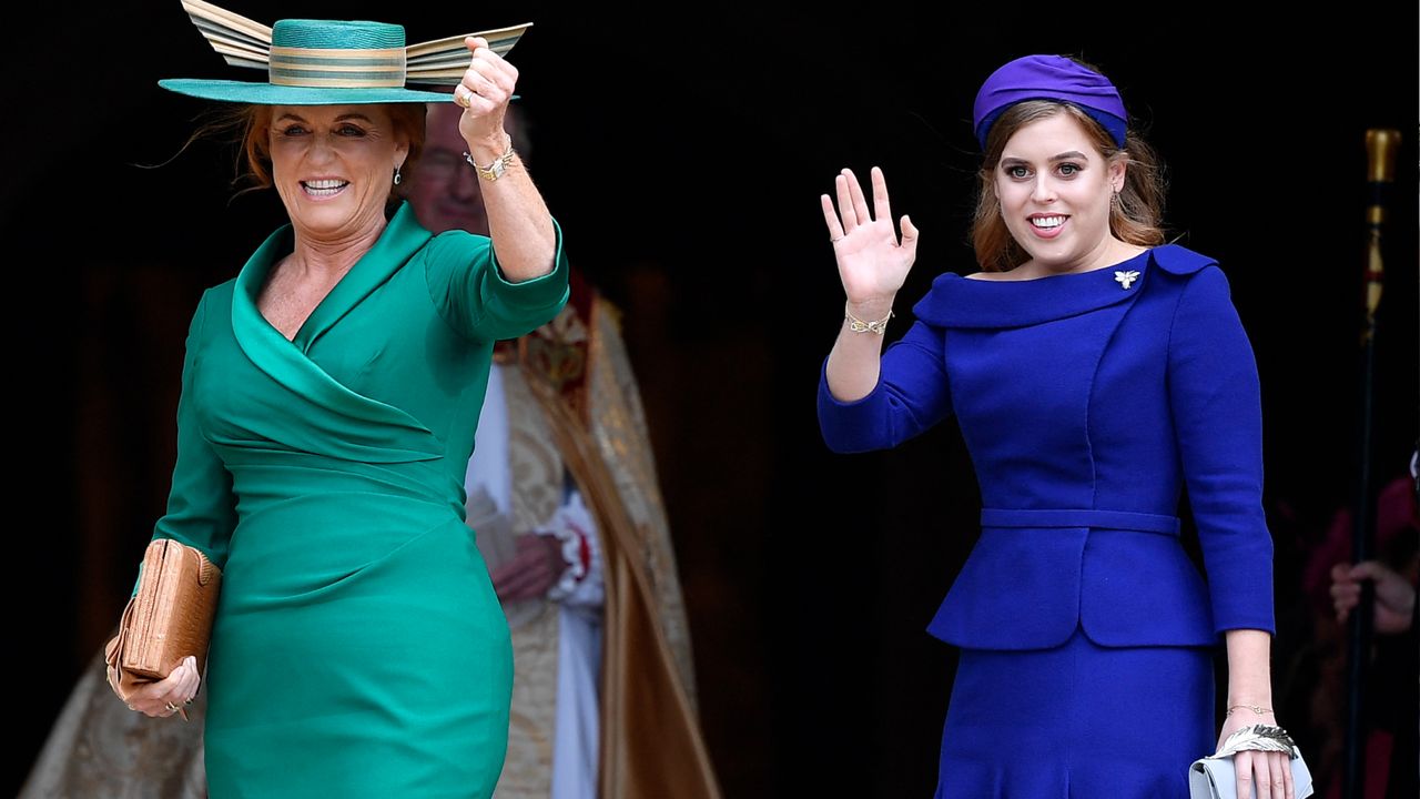 Sarah Ferguson wearing a green dress and matching hat smiling and standing next to Princess beatrice, who is dressed in a blue dress and headband and waving to the crowd on Princess Eugenie&#039;s wedding day