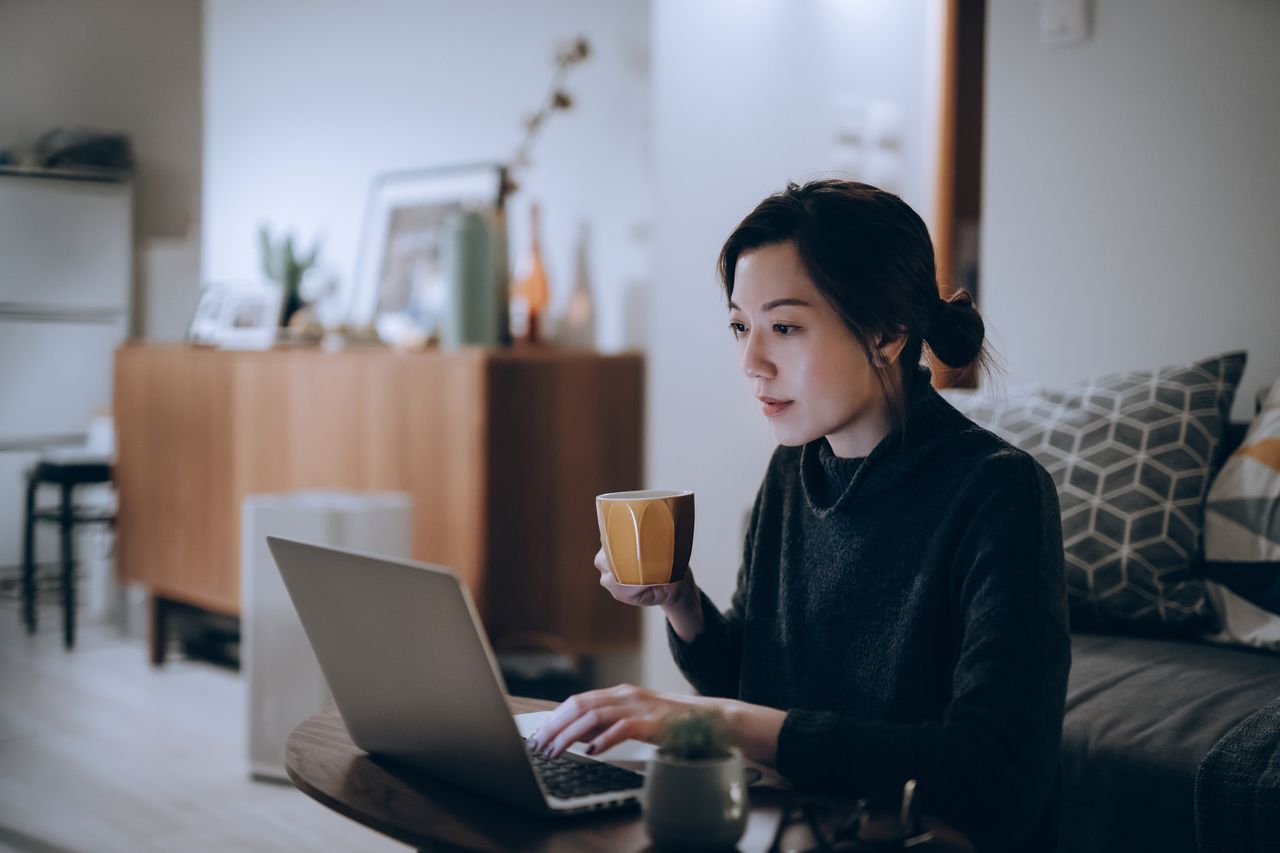 Young woman researching investments on a laptop. 