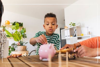 Child putting coins into a piggy bank while sitting at a dining room table at home