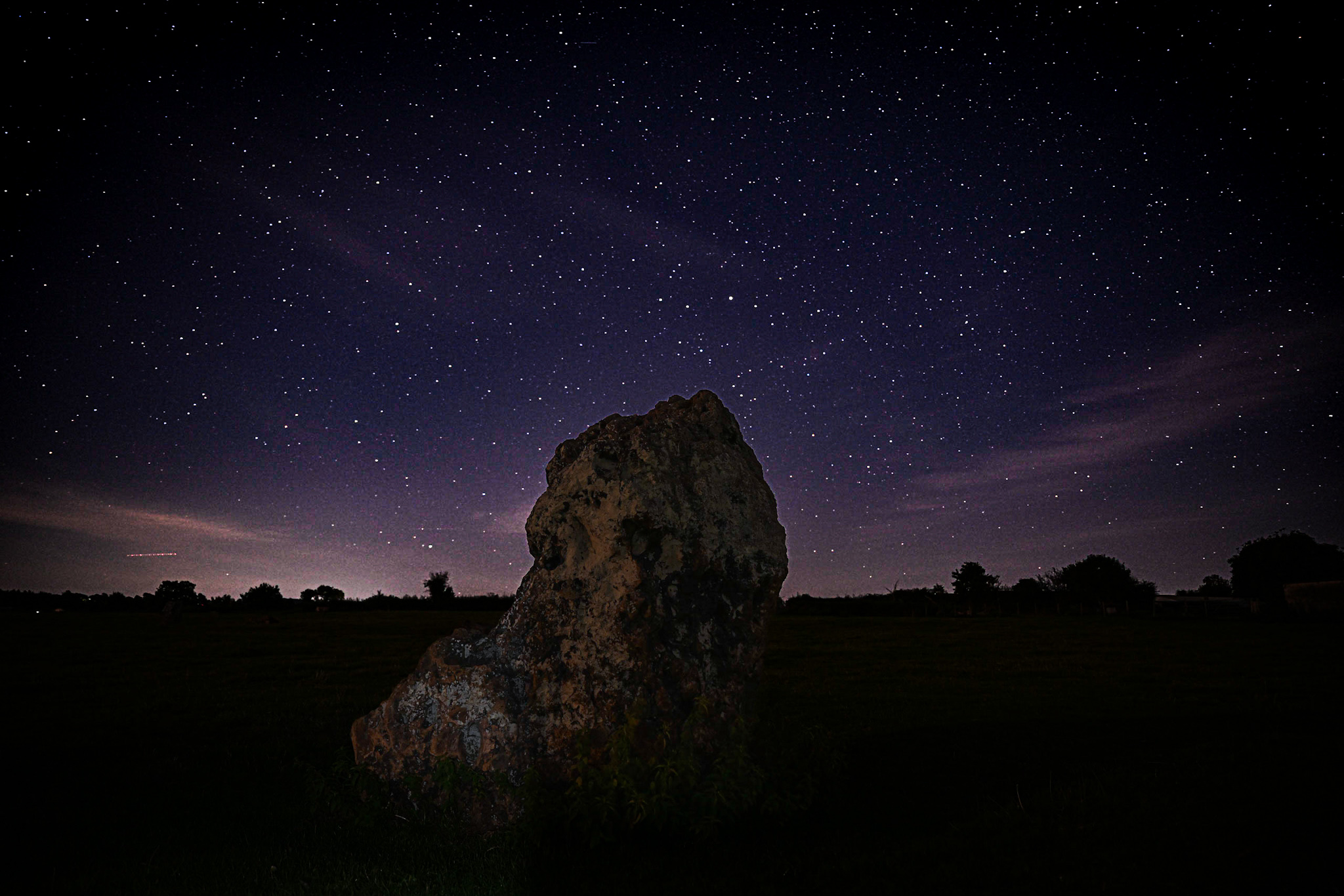 Voorbeeldafbeelding met de nachtelijke hemel boven een grote steen in een landschap op de voorgrond