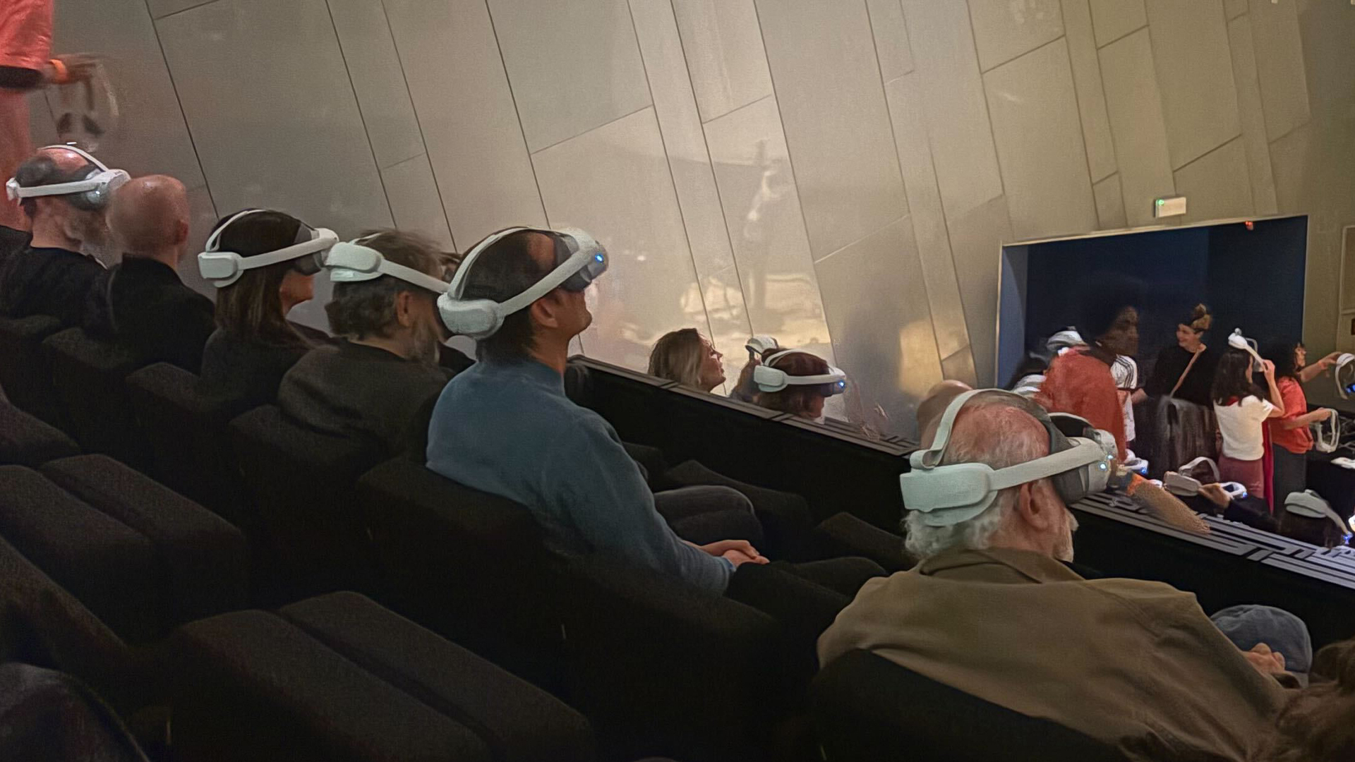 People seated in an auditorium wearing VR headsets