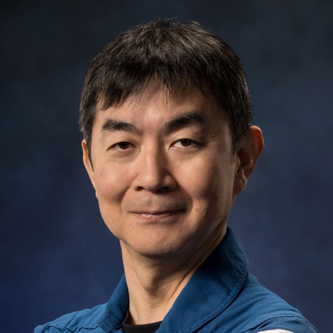 a man in a blue flight suit poses for a portrait