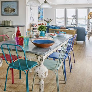 A coastal themed dining room with mismatched chairs and zinc topped dining table