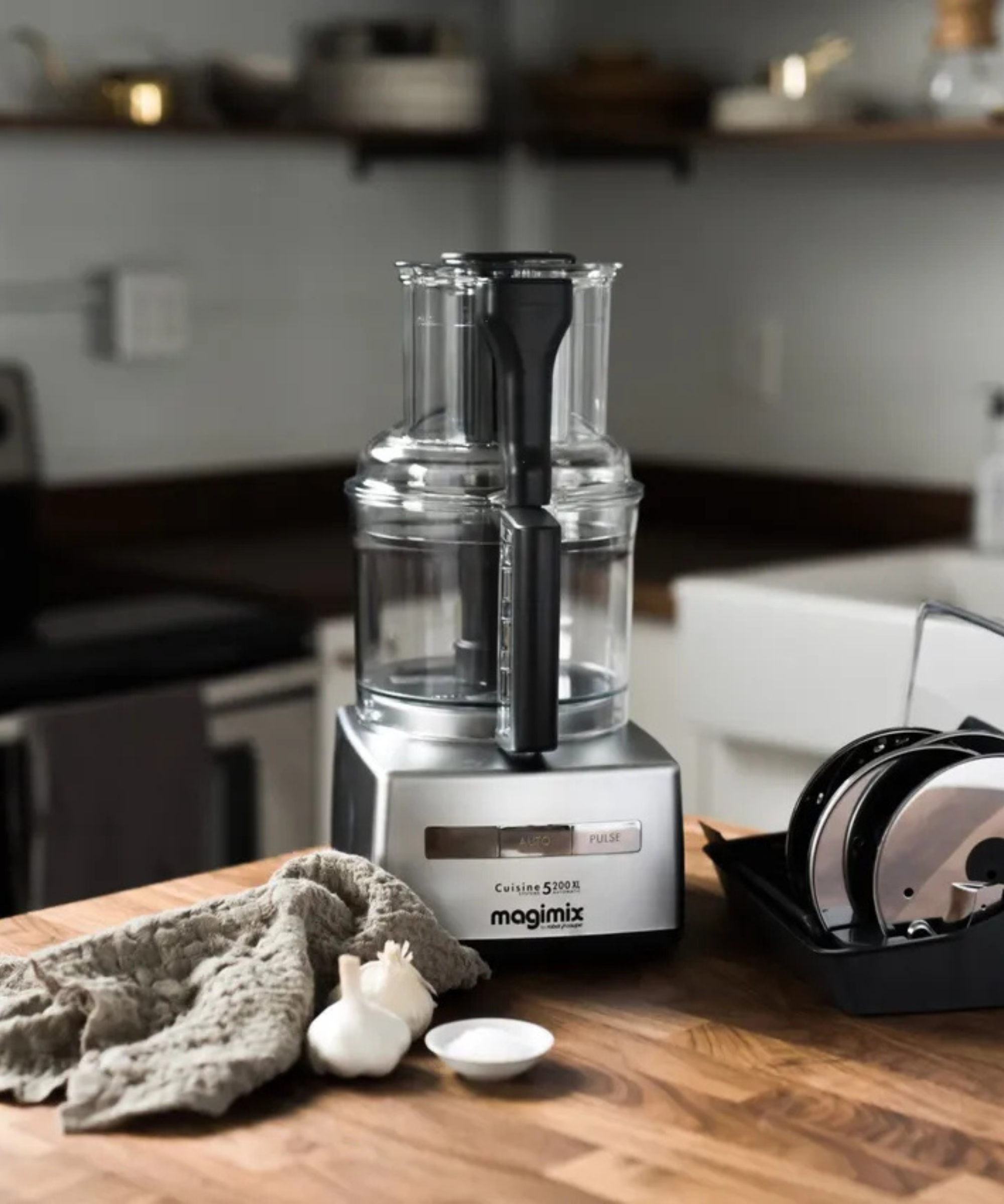 Magimix food processor on a wooden countertop with a wipe beside it