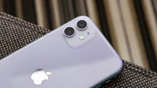 En närbild på baksidan av en vit iPhone 11 som fokuserar på dubbelkameran i ena hörnet.