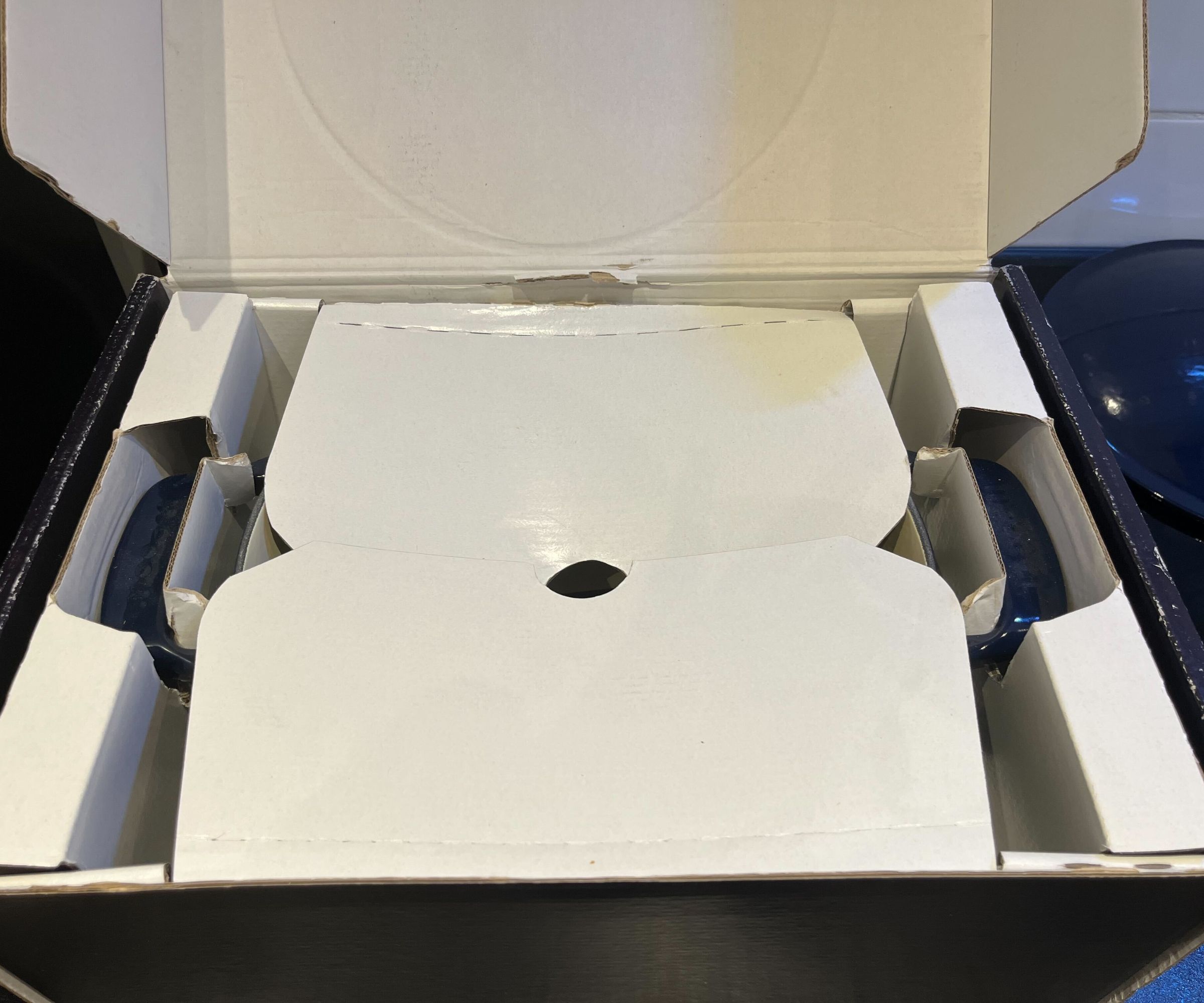 The Made In Dutch Oven box with the lid removed, showing cardboard folded over the main pan
