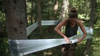 Woman wrapping plastic food wrap around trees