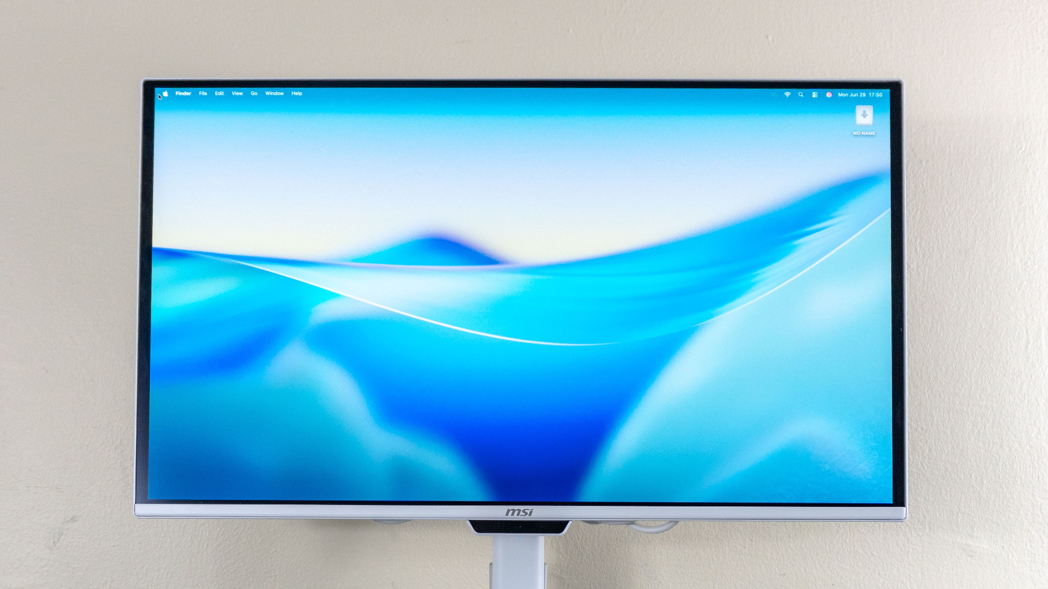 A close-up shot of the MSI Pro Max 271UPXW12G monitor showing an auto-mounted drive on the macOS desktop