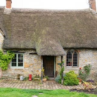 Exterior of a single-storey cottage with a thatched roof