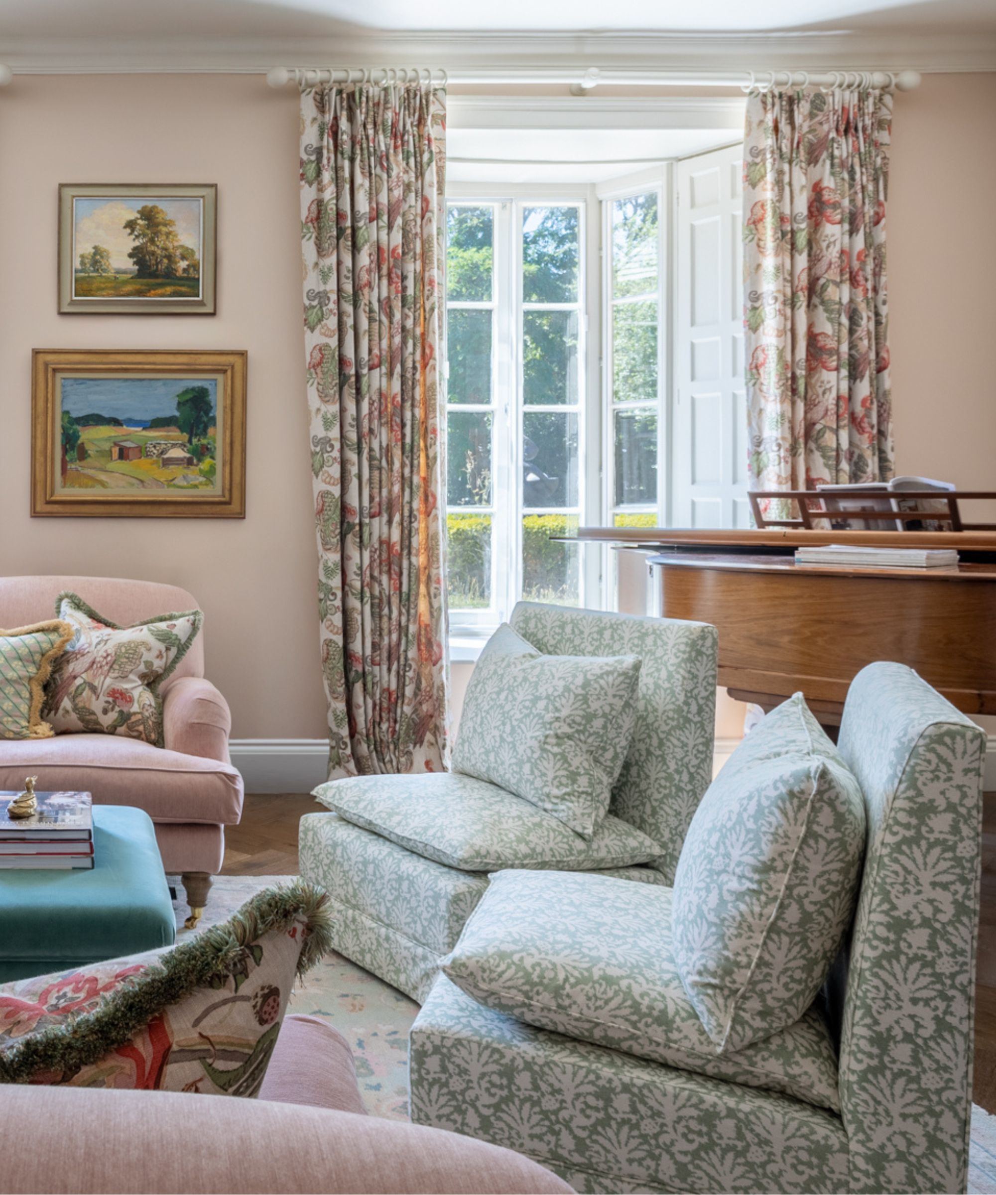 a light pink traditional english living room with a large oak piano and two blue patterned slipper chairs