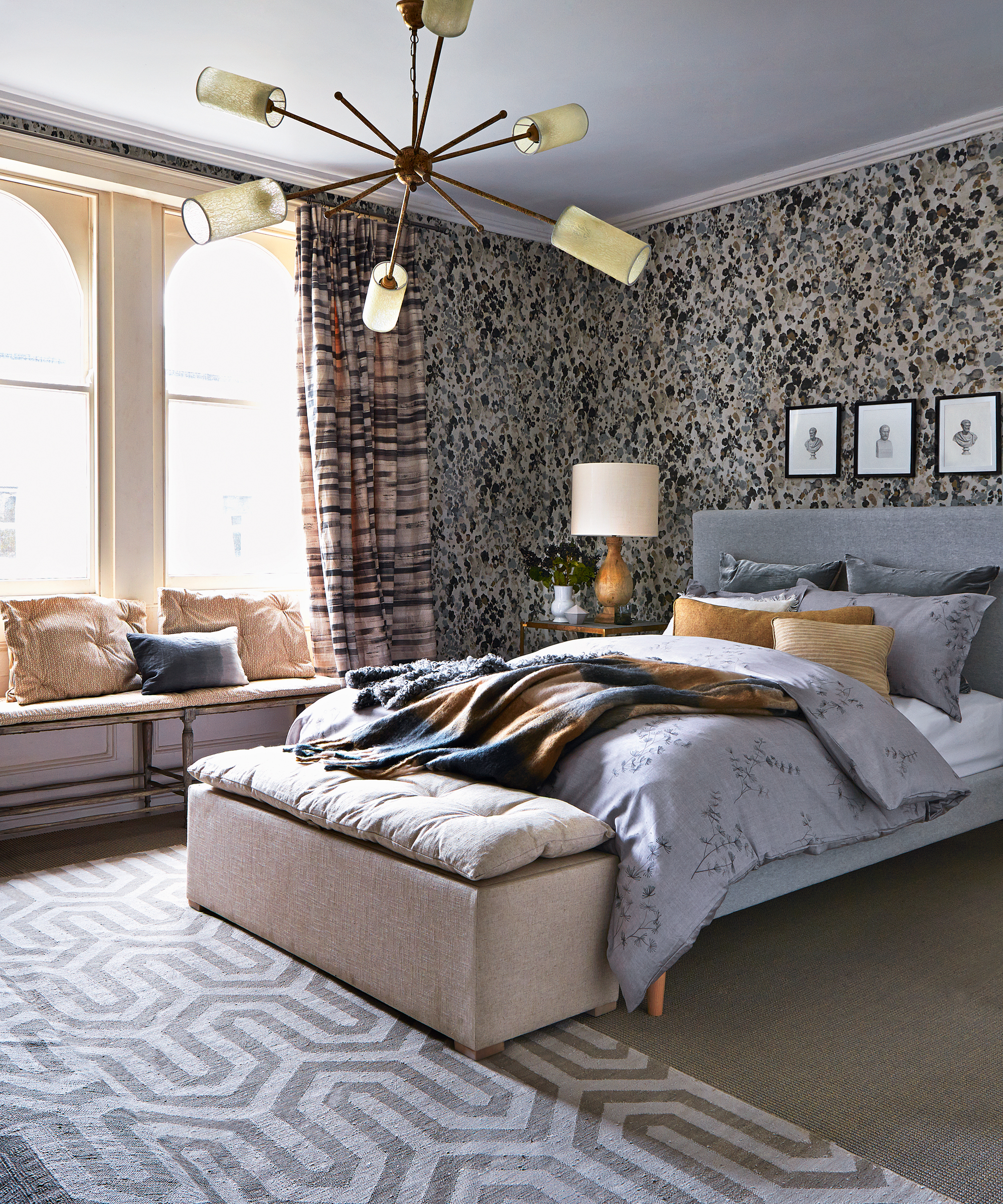 A grey bedroom idea with patterned wallpaper, curtains, rug and bed linen