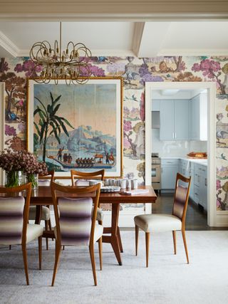 An evocative wallpaper of multi-hued trees backdrops a dining table.
