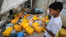A Palestinian boy inspects the site of an Israeli strike that killed Palestinians, gathered to collect water from a distribution point