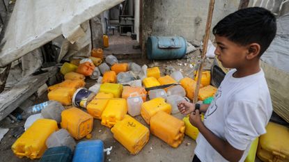 A Palestinian boy inspects the site of an Israeli strike that killed Palestinians, gathered to collect water from a distribution point