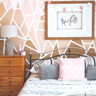 A bedroom with a geometric-print wallpaper in brown, pink and white