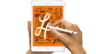 Hvid iPad mini holdt i venstre hånd, mens der tegnes på den med en penil i højre hånd