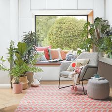 A white and airy living room with house plants and a window seat
