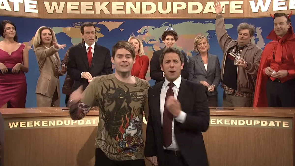 several snl cast members celebrating on the weekend update set