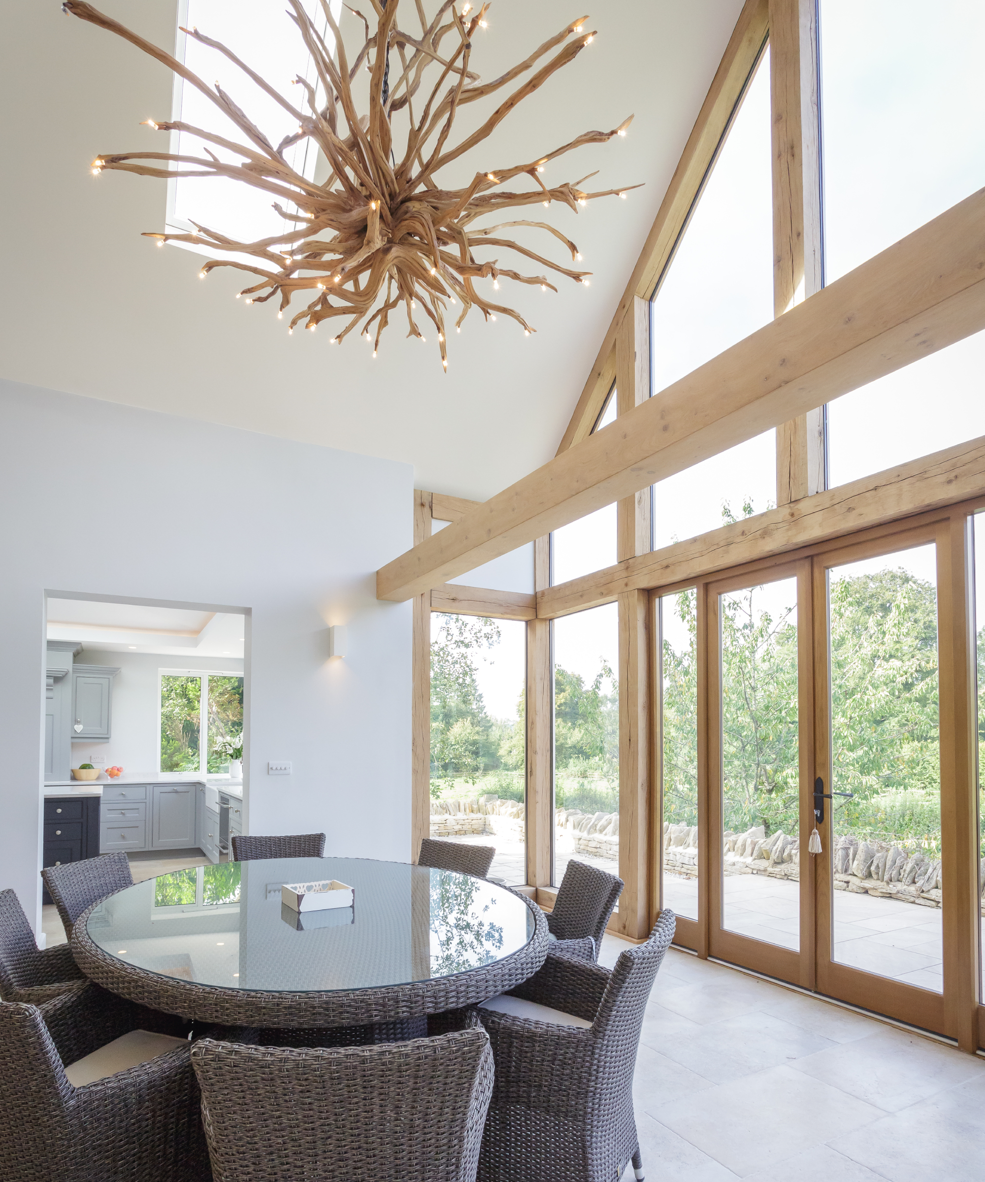 inside of dining area in barn with double height ceiling, large wooden patio doors and architectural glazing